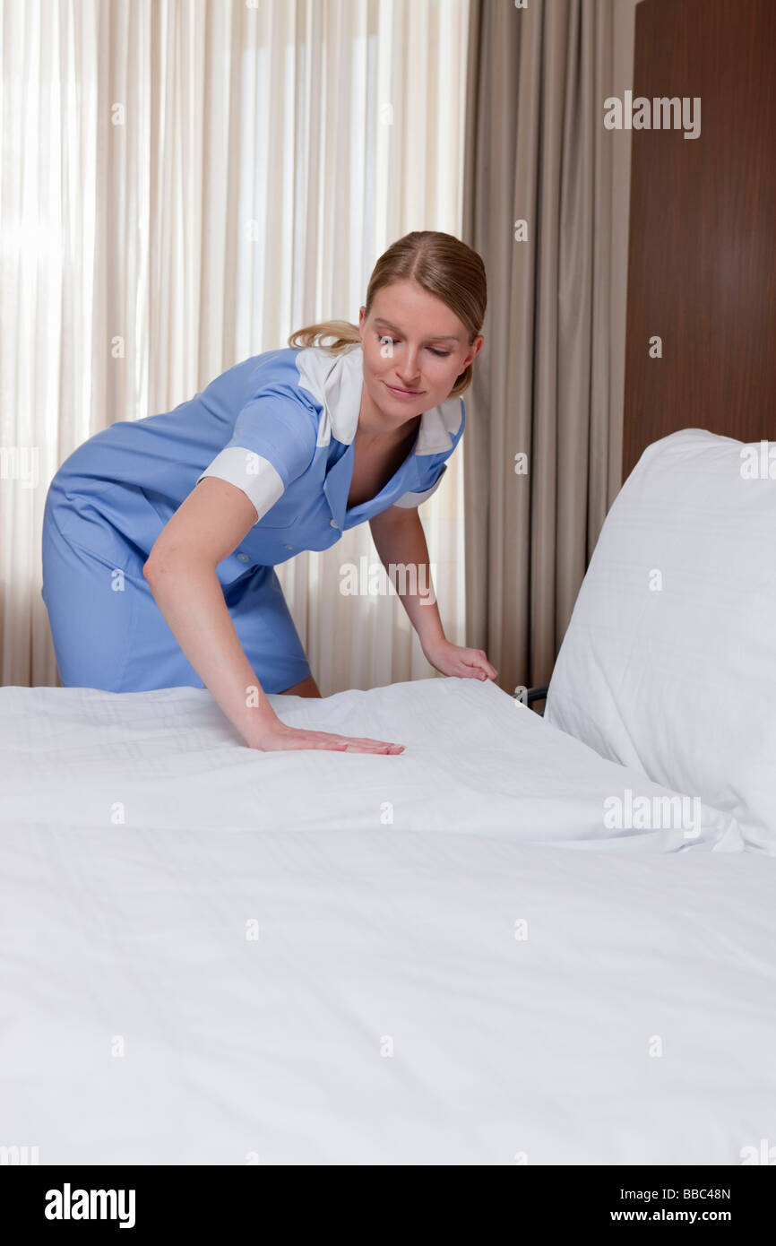 Femme de chambre faire un lit dans la chambre d'hôtel Photo Stock - Alamy