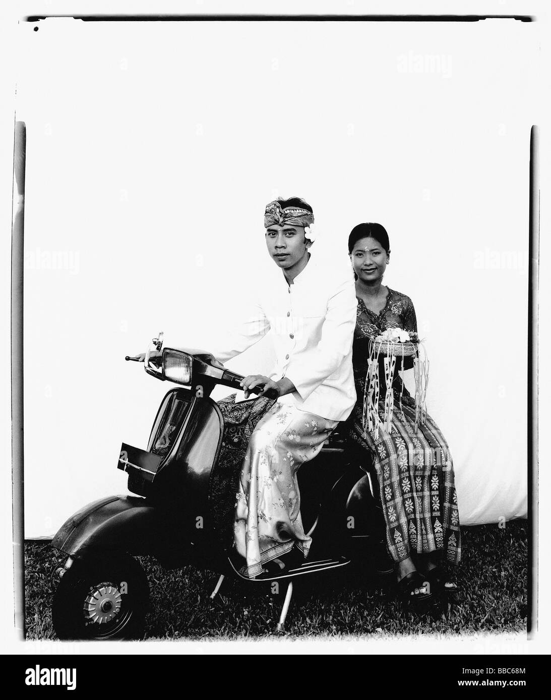 L'INDONÉSIE, Bali, Ubud, Bali wedding couple en tenue de cérémonie, assis sur le scooter, femme portant à l'épargne. Banque D'Images
