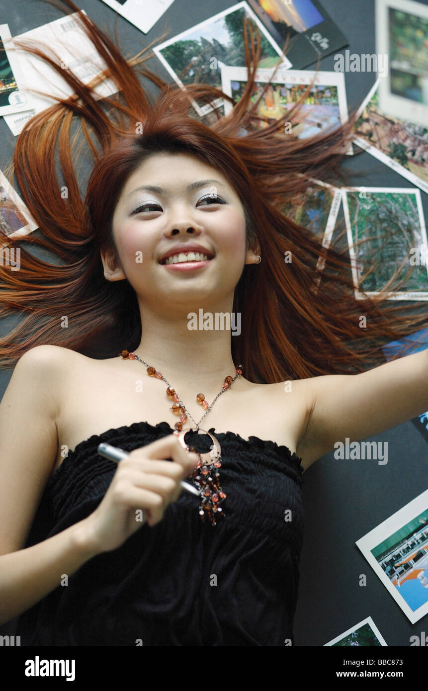 Woman lying on floor, cartes postales réparties autour de son Banque D'Images