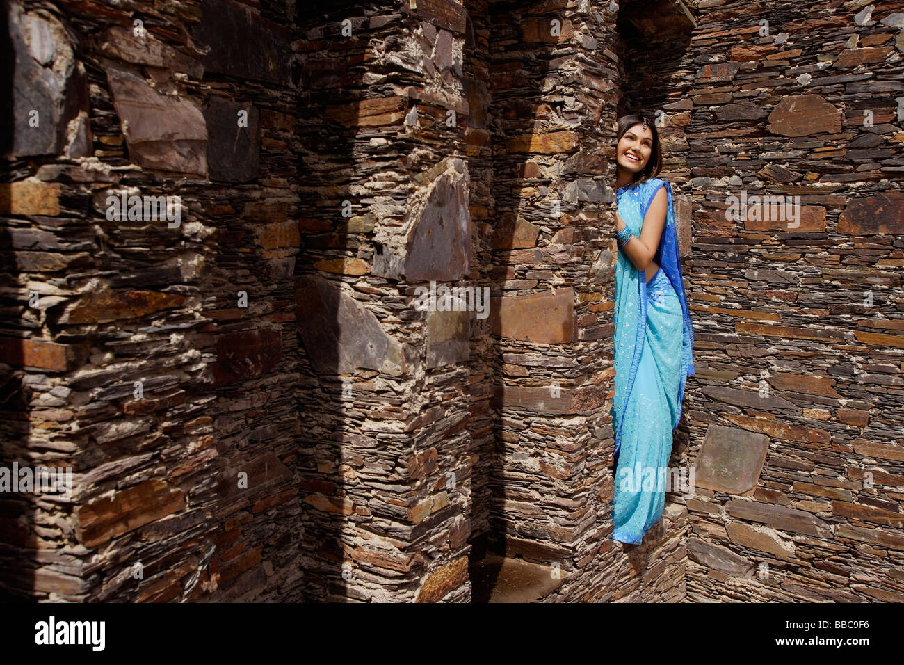 Jeune femme en sari, d'oeil de derrière le pilier de brique Banque D'Images