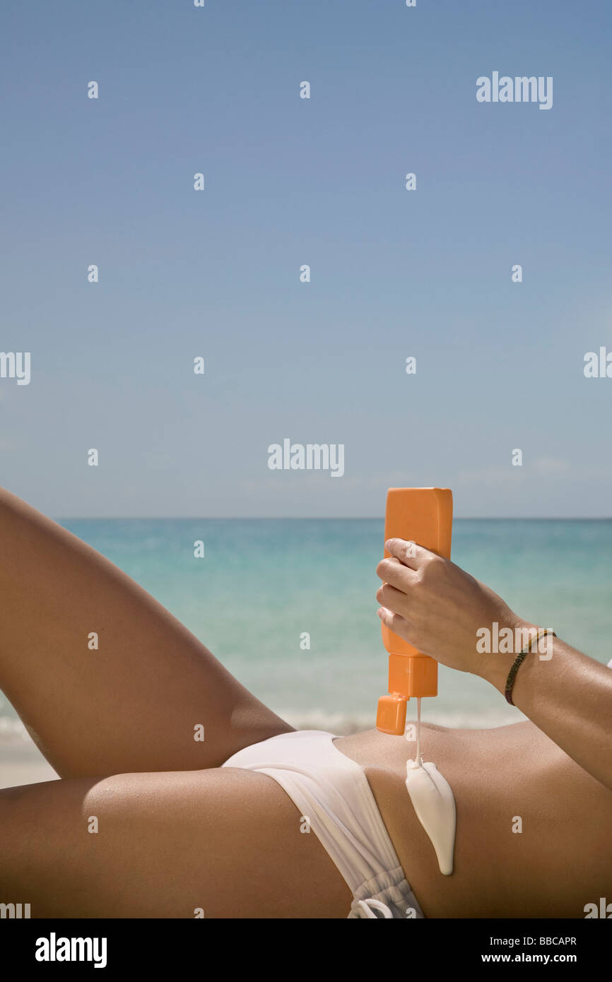 Femme d'utiliser un écran solaire Banque D'Images