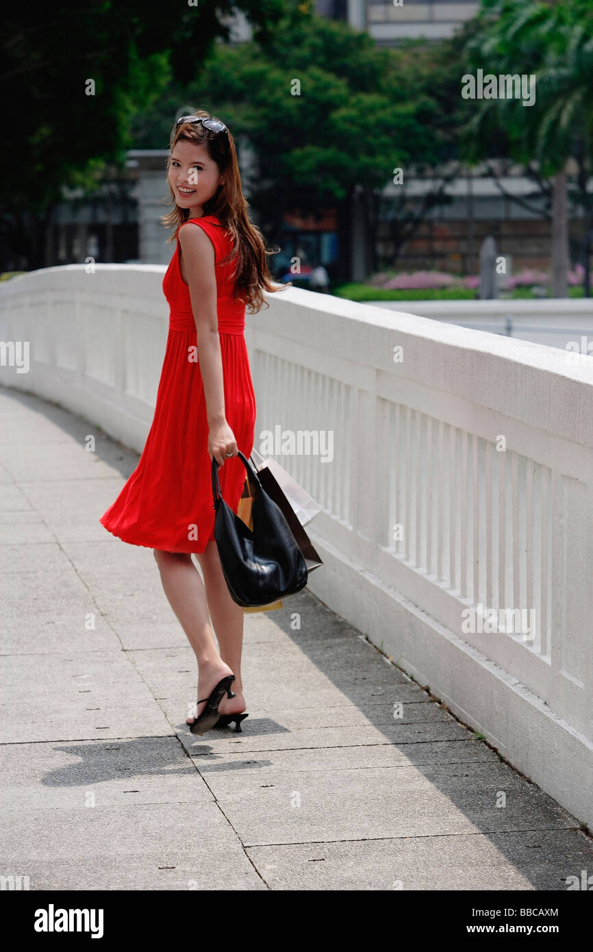 Femme en robe rouge, shopping looking over shoulder Banque D'Images