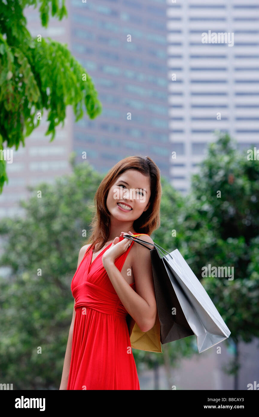 Femme en robe rouge carrying shopping bags, ville Banque D'Images