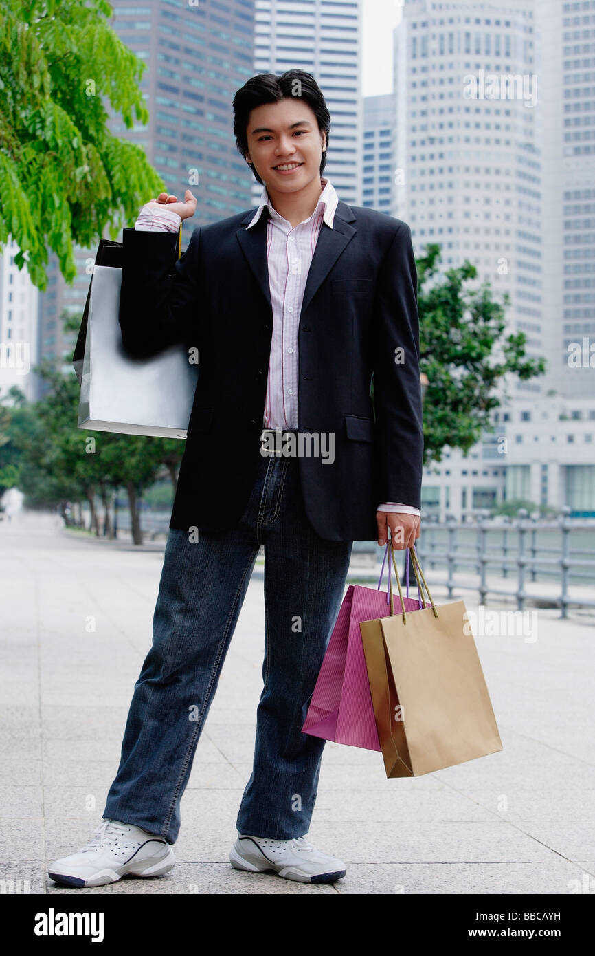 Man standing with shopping bags, smiling at camera Banque D'Images
