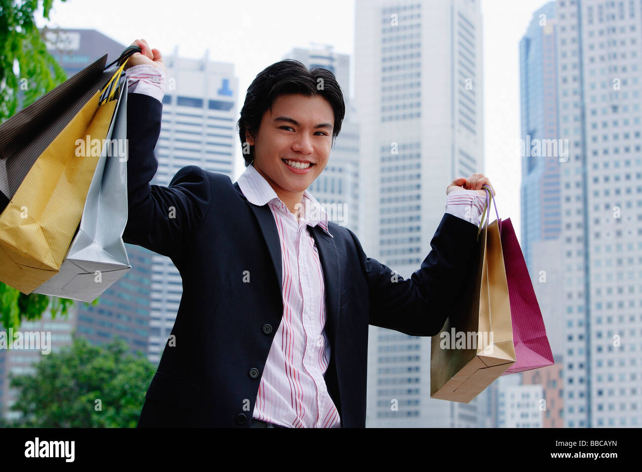 Man carrying shopping bags, smiling at camera Banque D'Images