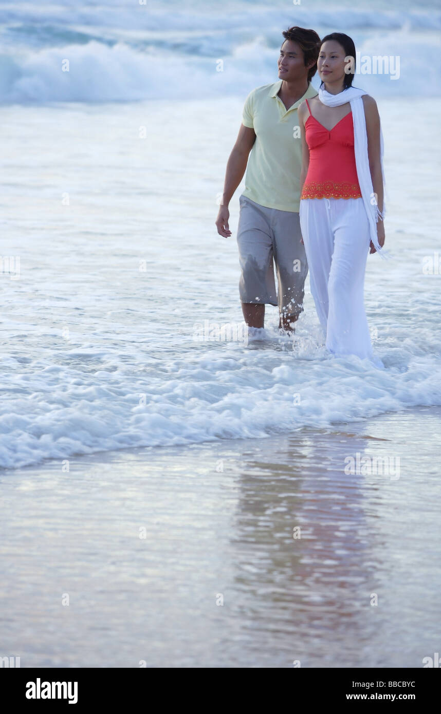 Couple walking on beach, dans l'eau jusqu'aux chevilles Banque D'Images