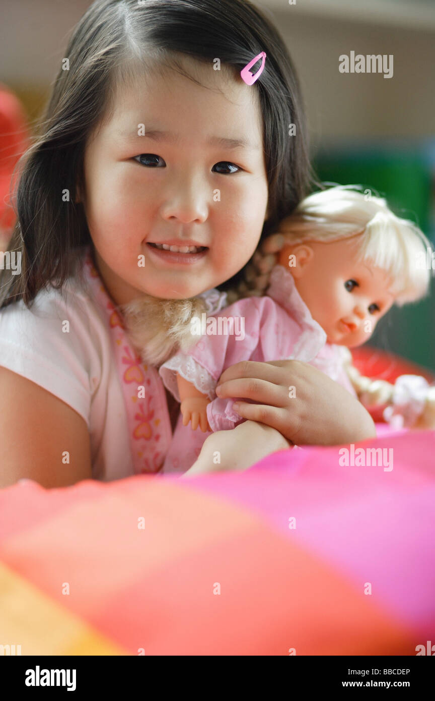 Girl holding a doll, looking at camera Banque D'Images