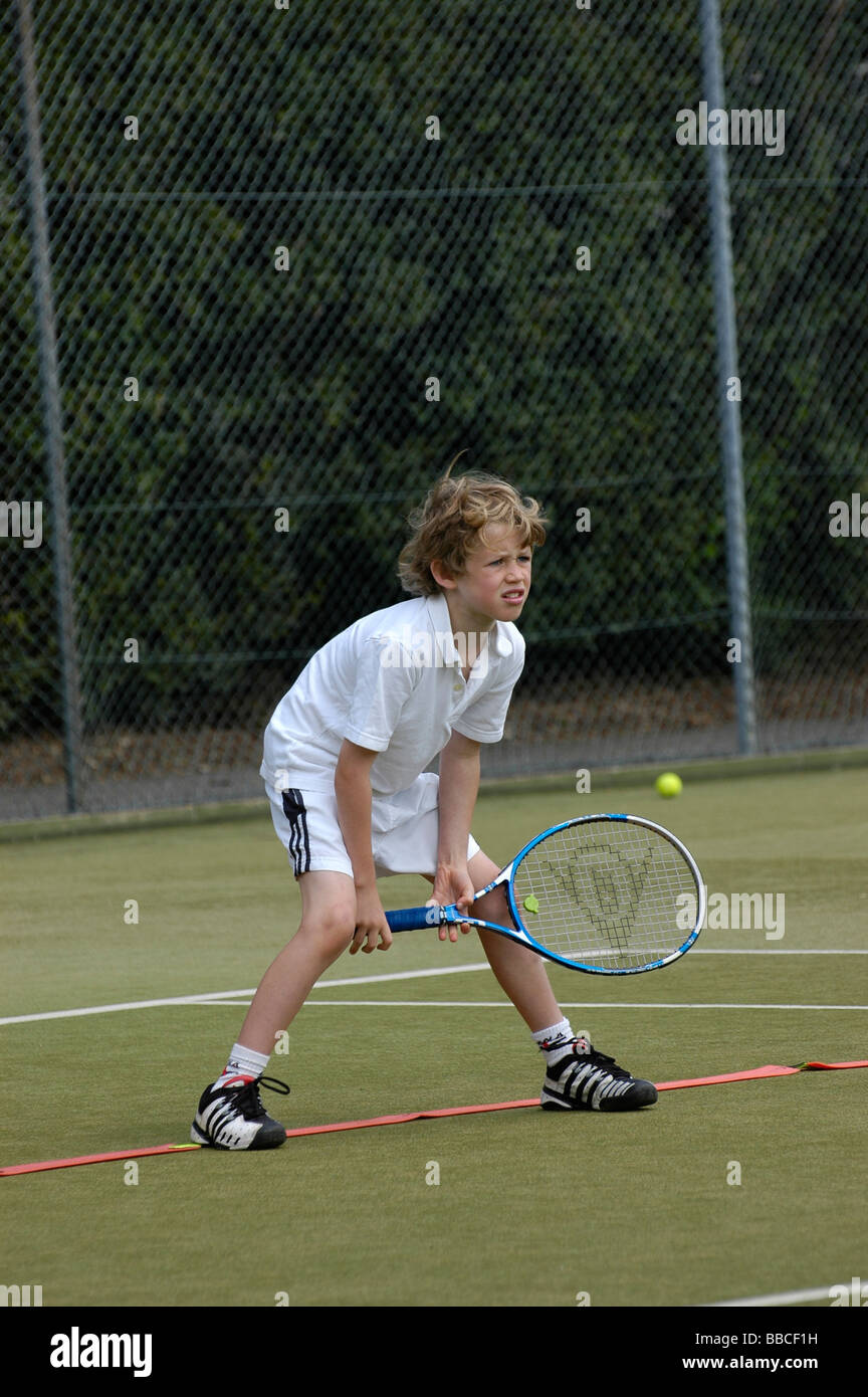 Un jeune garçon jouant au tennis dans une position d'attente Banque D'Images