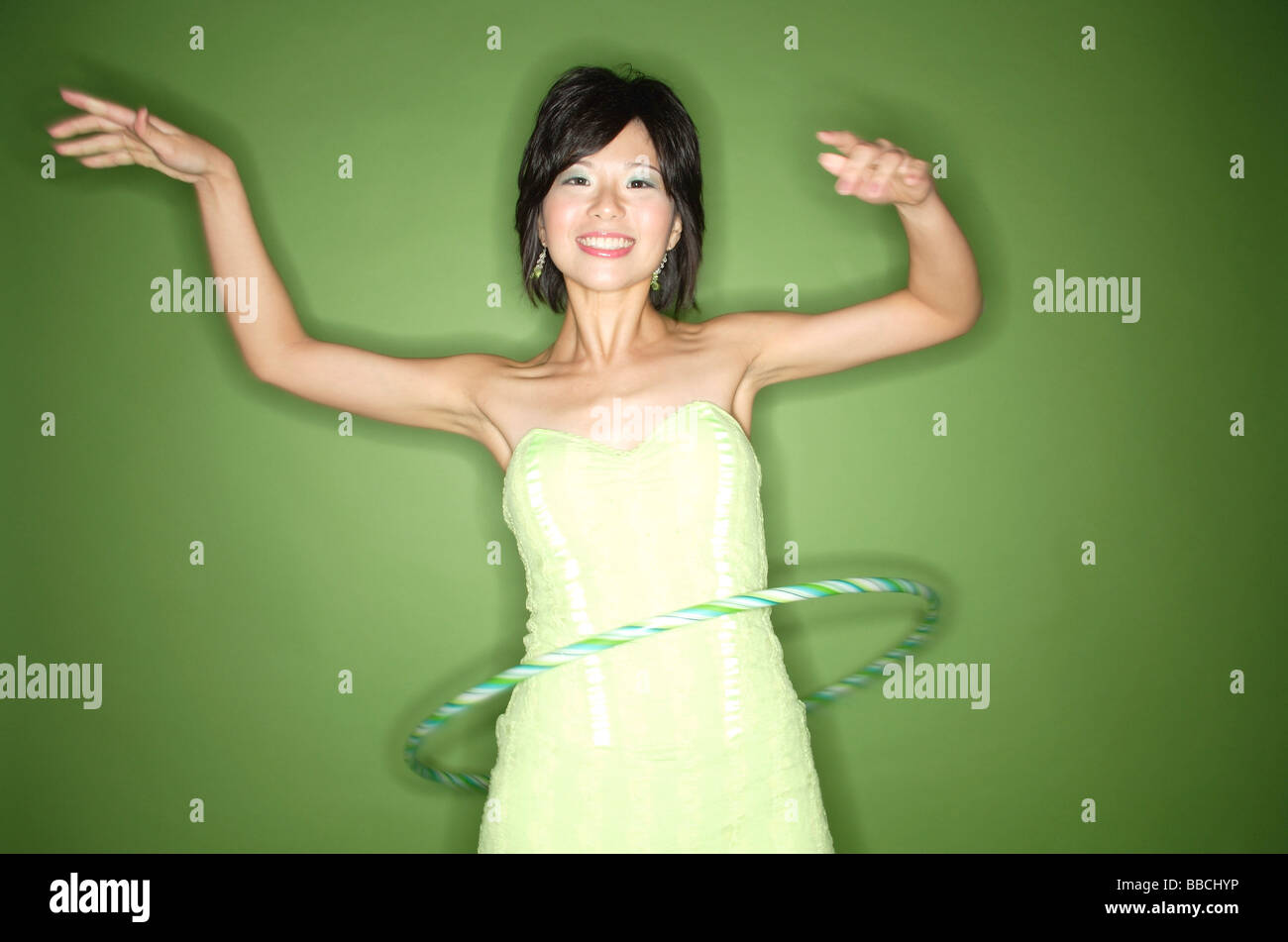 Femme en robe bustier vert à l'aide de hoola hoop Banque D'Images