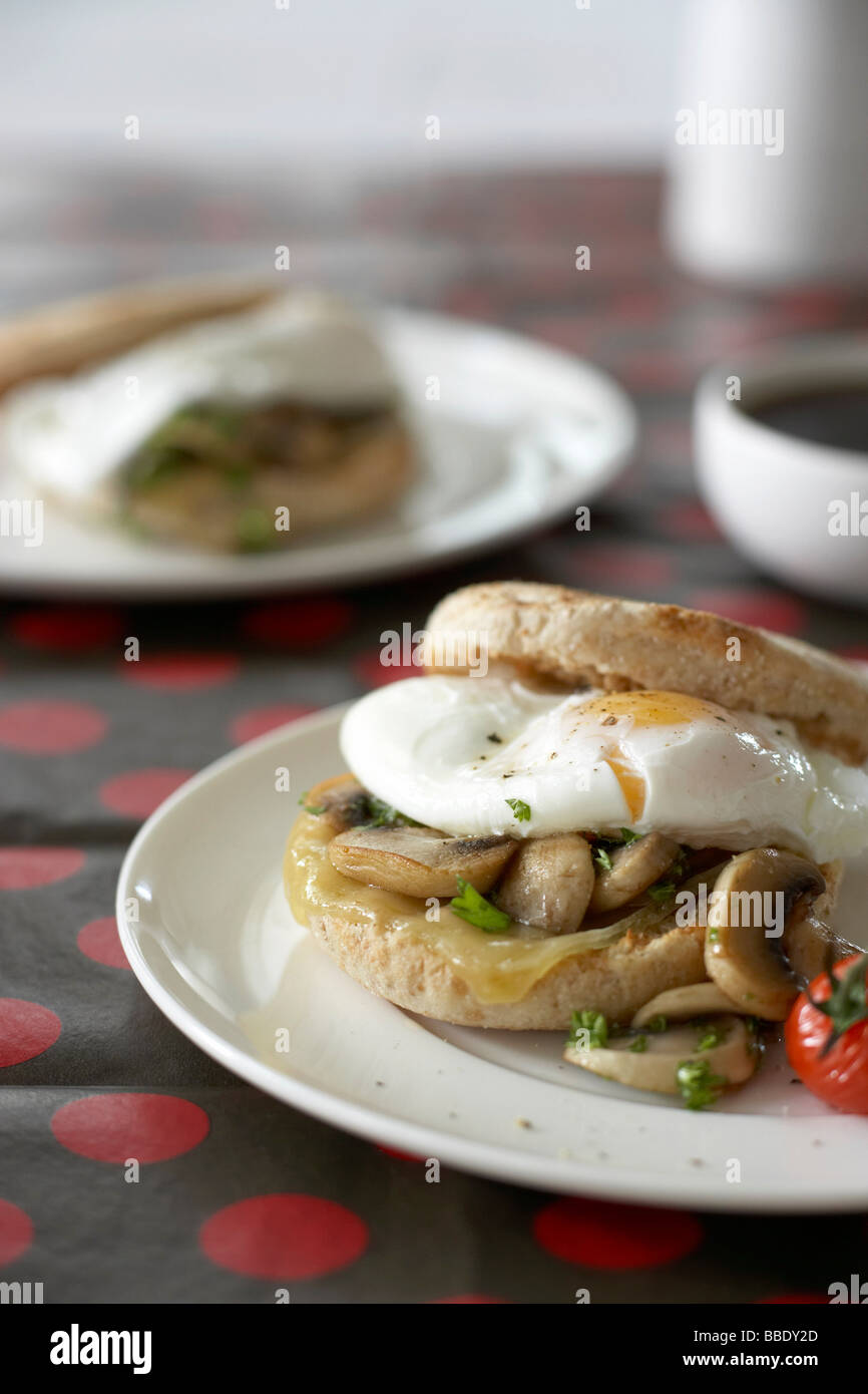 Œufs pochés avec champignons sautés et tomate grillée sur muffin anglais au blé entier Banque D'Images