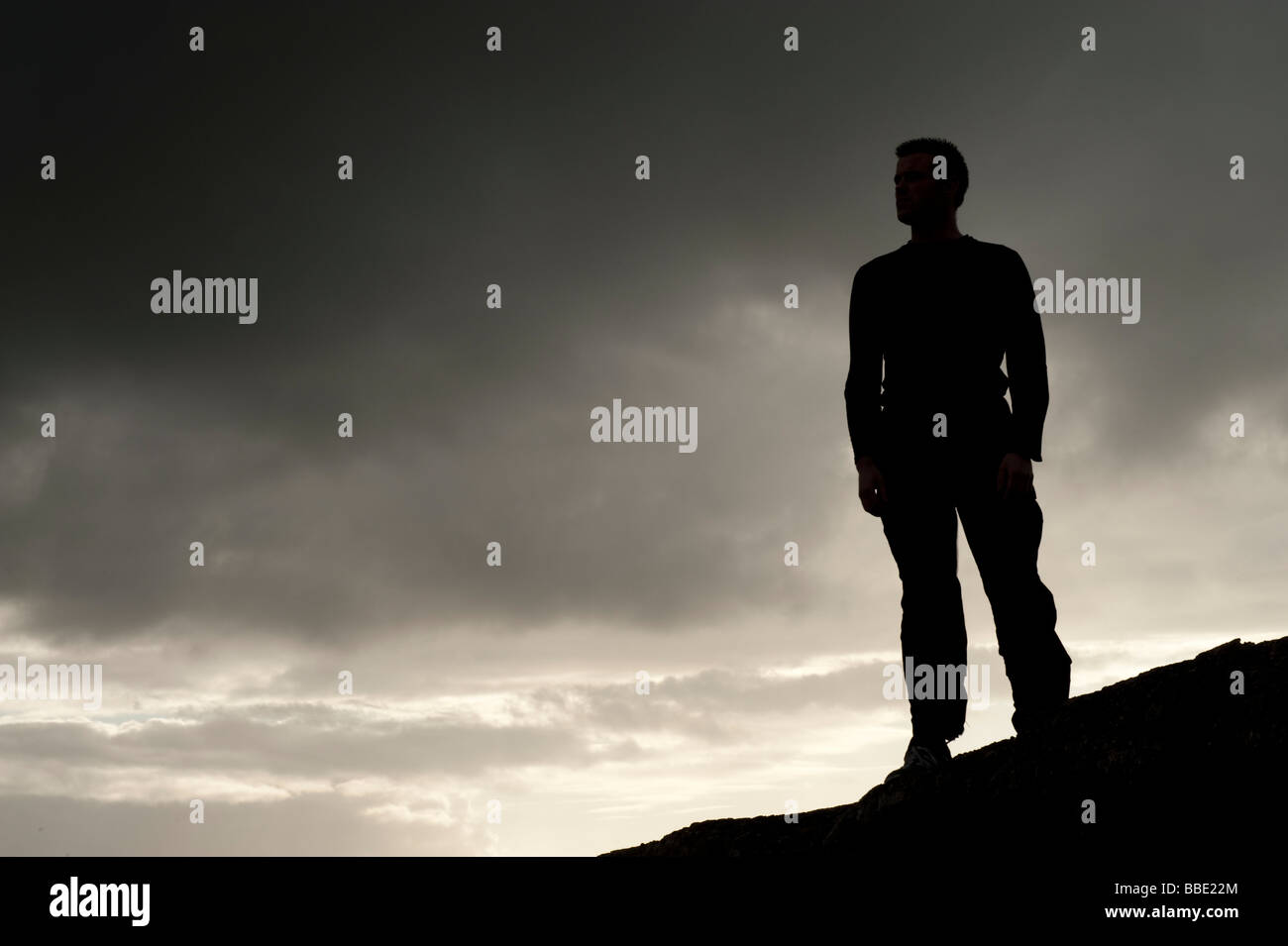 Silhouette d'un homme debout sur skyline contre un ciel noir orageux moody de couver Banque D'Images