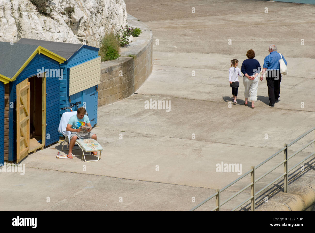 Broadstairs, Kent, Angleterre, Royaume-Uni. Louisa Bay. La marche de la famille homme passé par cabanes de plage Banque D'Images