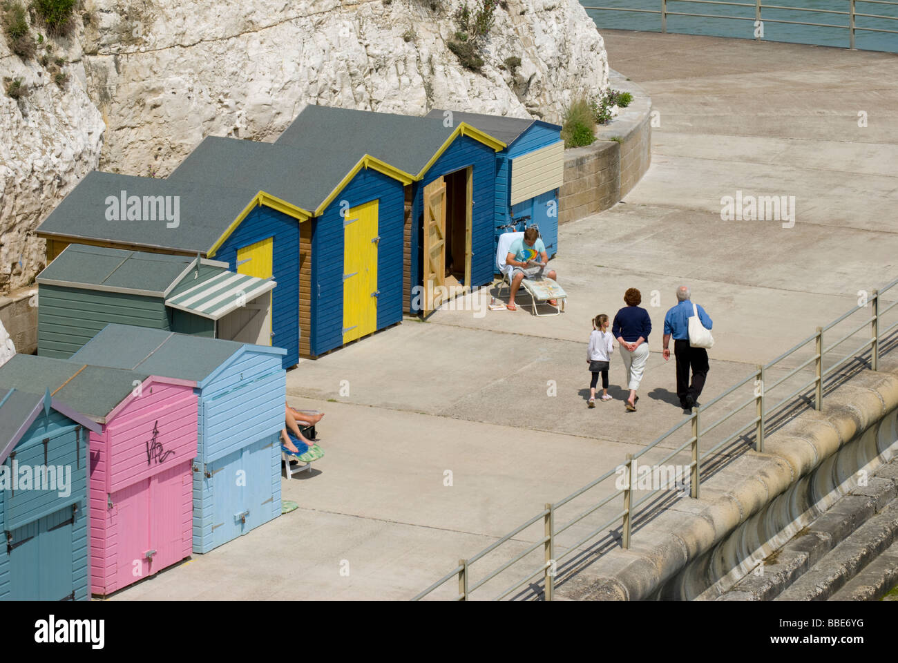 Broadstairs, Kent, Angleterre, Royaume-Uni. Louisa Bay. La marche de la famille homme passé par cabanes de plage Banque D'Images