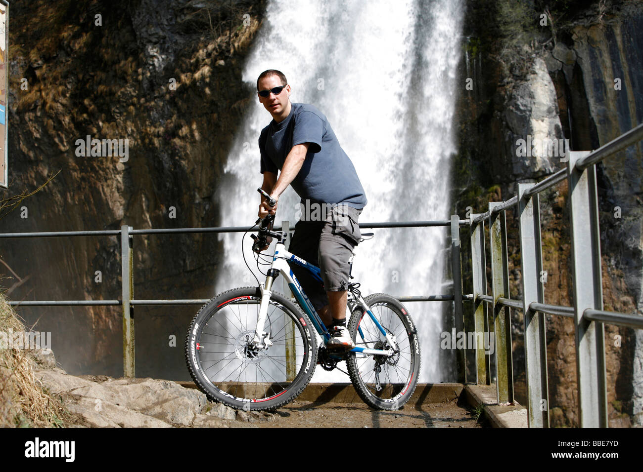 L'équilibrage de motards sur son vélo en face de la vue sur la cascade de tonitruantes, Rinquelle Rin Printemps, et Seerenbach, Betl Banque D'Images