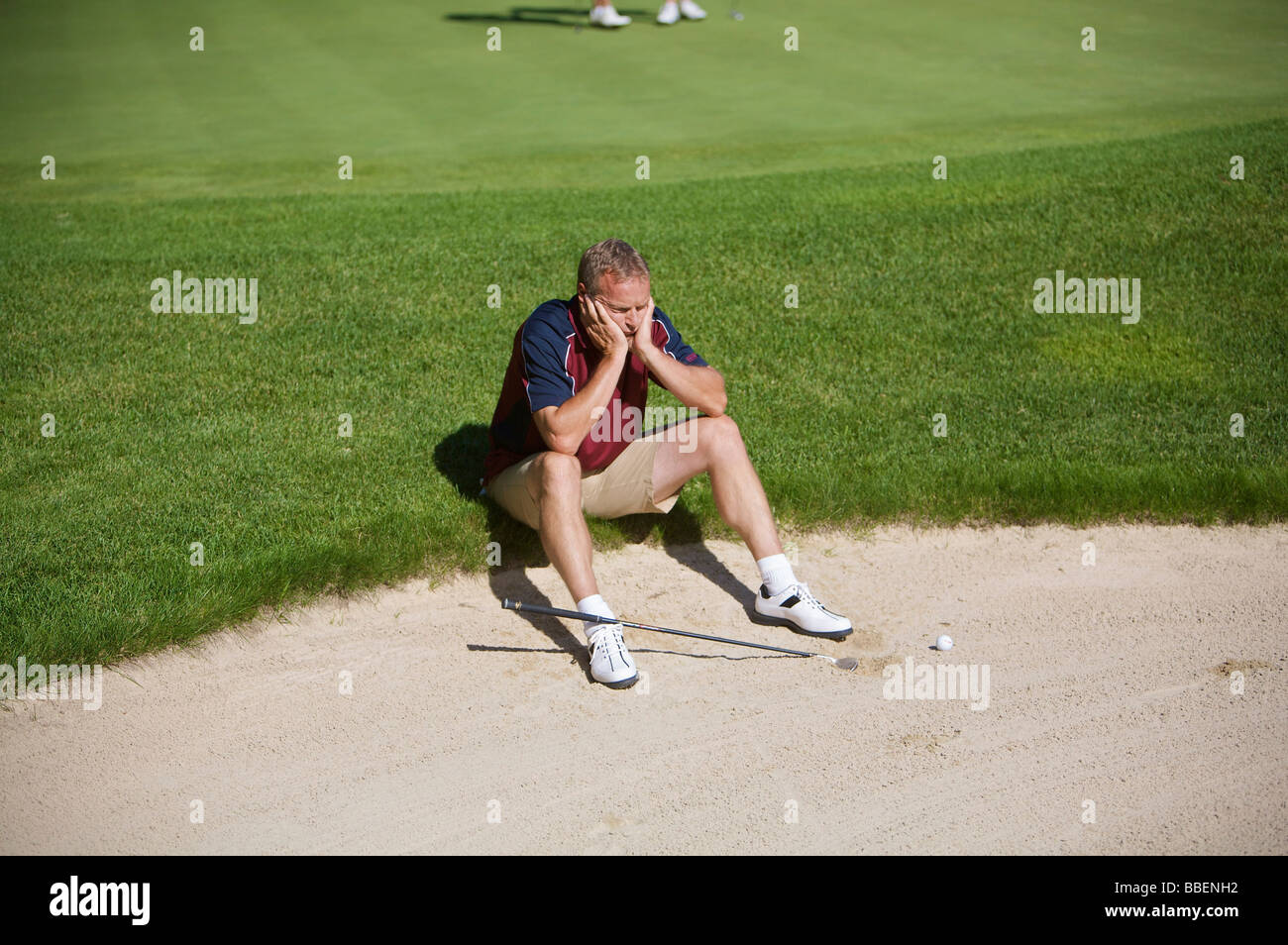 Homme assis par fosse de sable on Golf Course Banque D'Images
