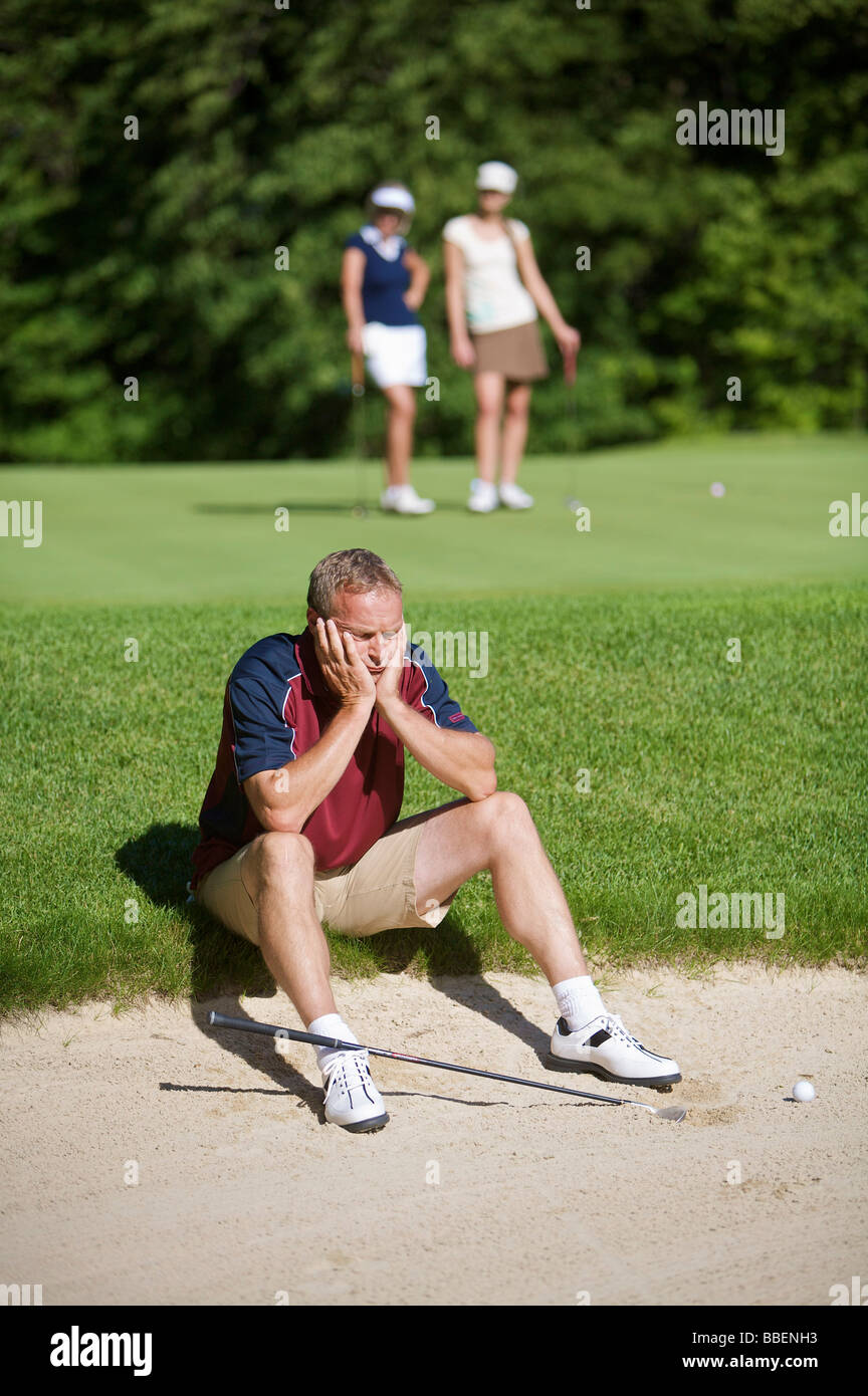 Homme assis par fosse de sable on Golf Course Banque D'Images