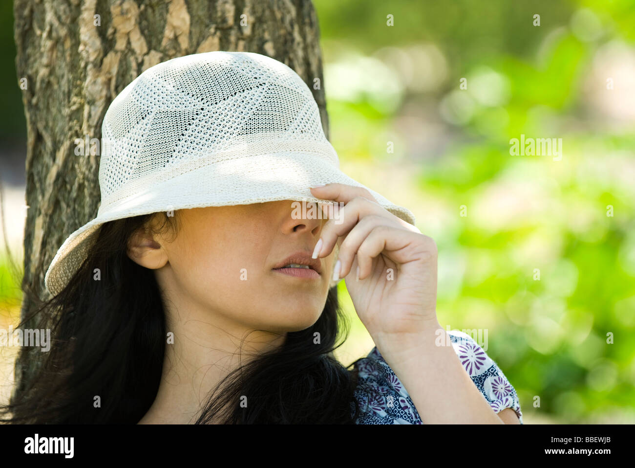 Jeune femme tirant chapeau de soleil au-dessus des yeux Photo Stock - Alamy