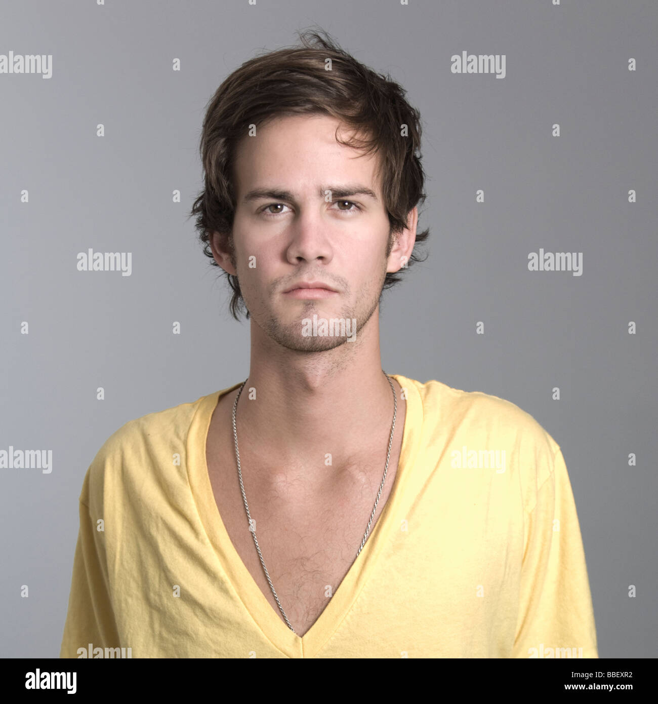 Portrait de l'homme en jaune à col en v sur fond gris Banque D'Images