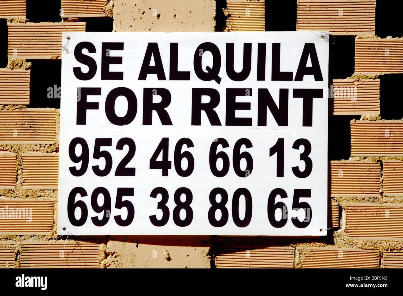 Bilingue pour laisser sign signe en deux langues sur un mur de brique à Fuengirola, Costa del Sol, Andalousie, Espagne, Europe Banque D'Images