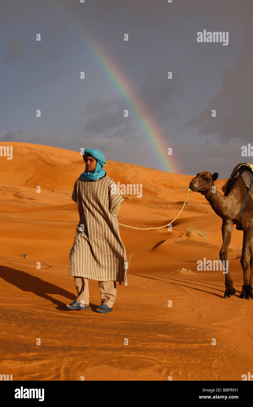 Afrique, Afrique du Nord, Maroc, Sahara, Merzouga, Erg Chebbi, Berbère Tribesman menant Camel, arc-en-ciel dans le désert Banque D'Images