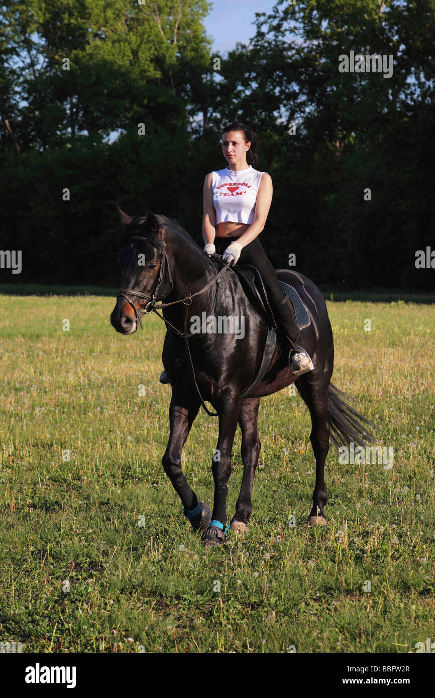 Teenage girl riding horse in field Banque D'Images