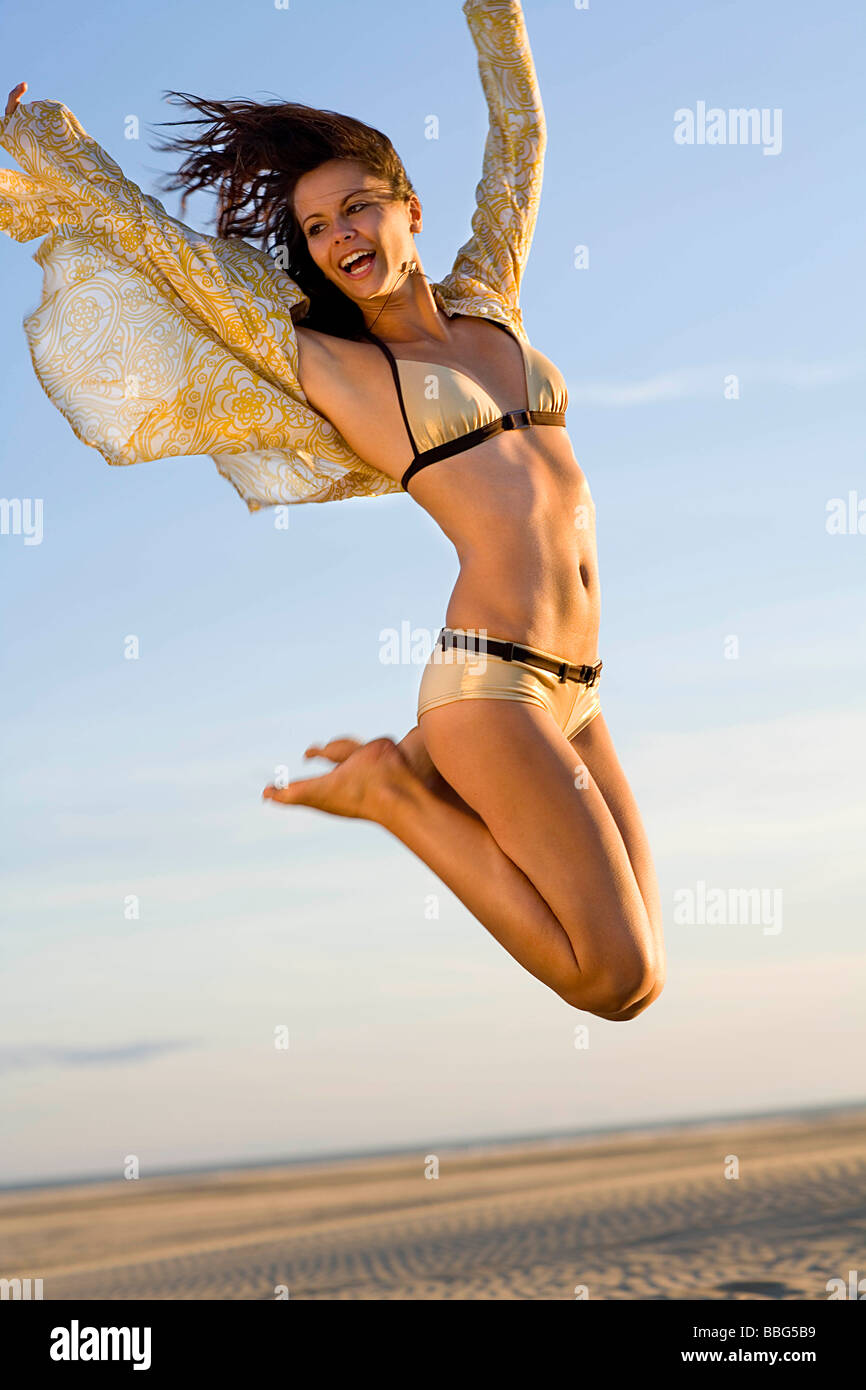 Jeune femme sauts à beach Banque D'Images