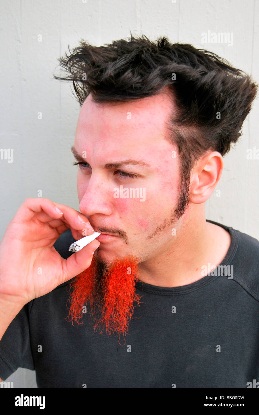 Médicaments, jeune homme avec barbe rouge-noir, fumer un joint, cigarette roulée à la main Banque D'Images