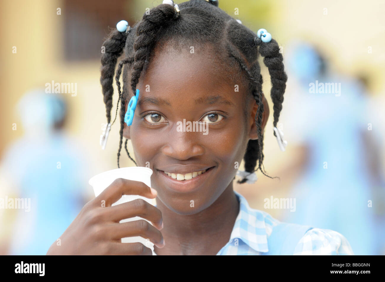 Black smiling schoolgirl boire une tasse d'eau Banque D'Images