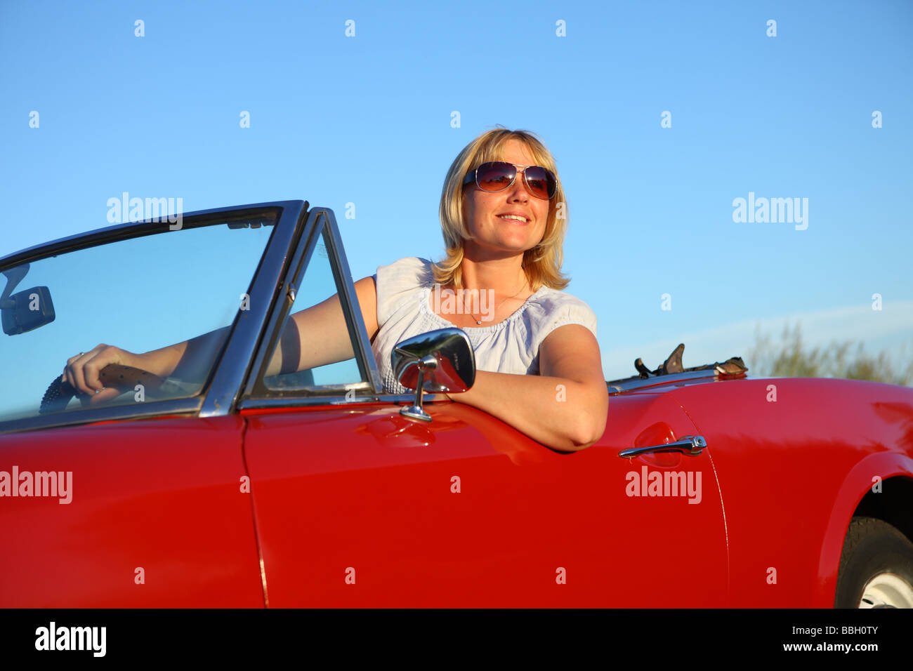 Jeune femme en rouge voiture décapotable Banque D'Images