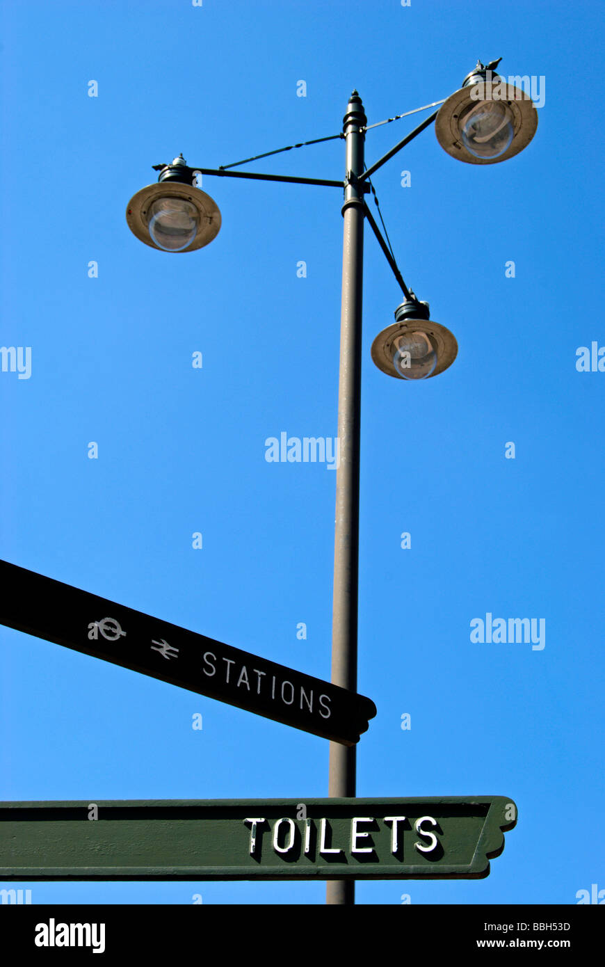 Direction de pointeurs pour les toilettes et les stations, avec des lampes de rue en arrière-plan Banque D'Images