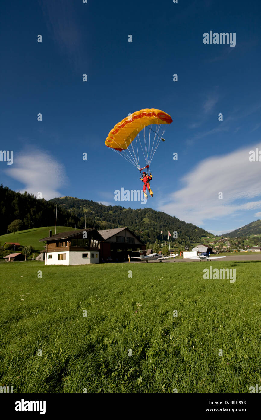 Parachutiste est volant sous canoy et va atterrir sur une belle pelouse de la paix. Le parachute stable dans le ciel bleu. Banque D'Images