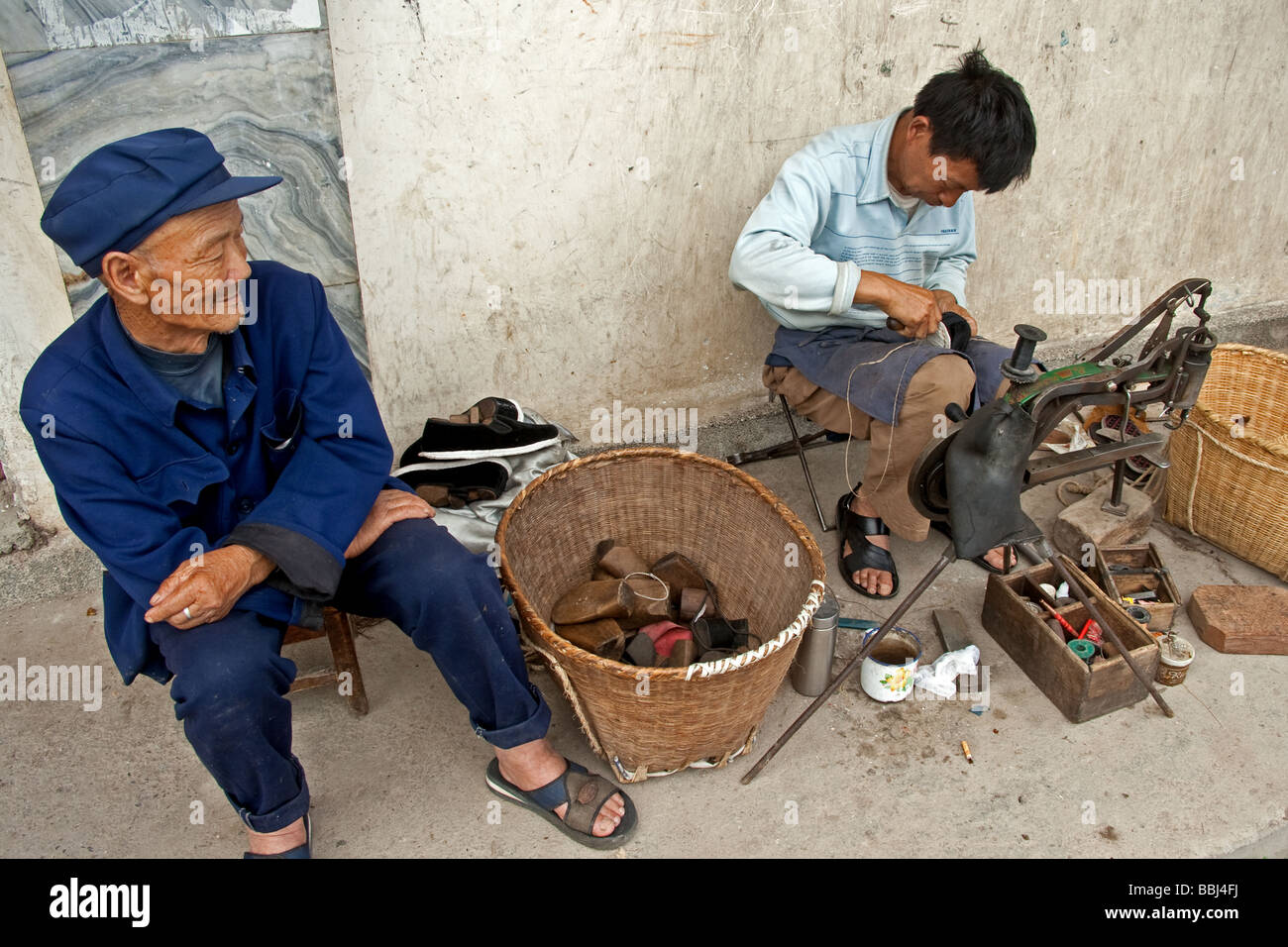 L'homme Chinois Han attendait patiemment ses chaussures pour être réparé à Dali, Yunnan, Chine Banque D'Images