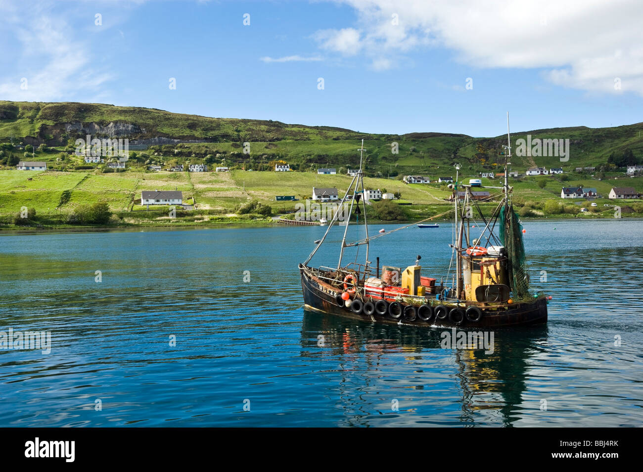 Un bateau de pêche arrive à l'UIG Harbour en Skye Ecosse sur une journée de printemps ensoleillée Banque D'Images