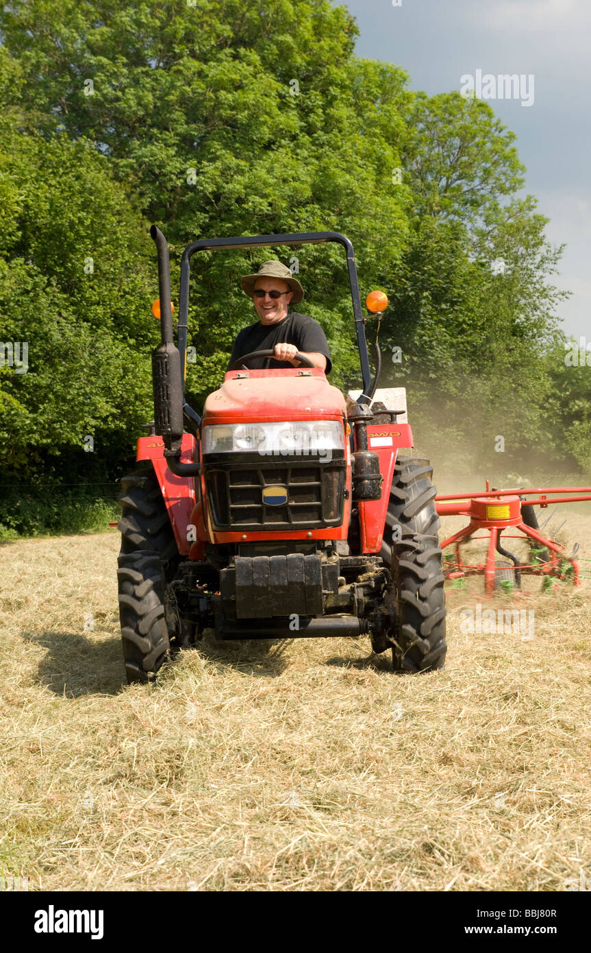 Hay en les faisant tourner le tracteur et l'agriculteur Banque D'Images