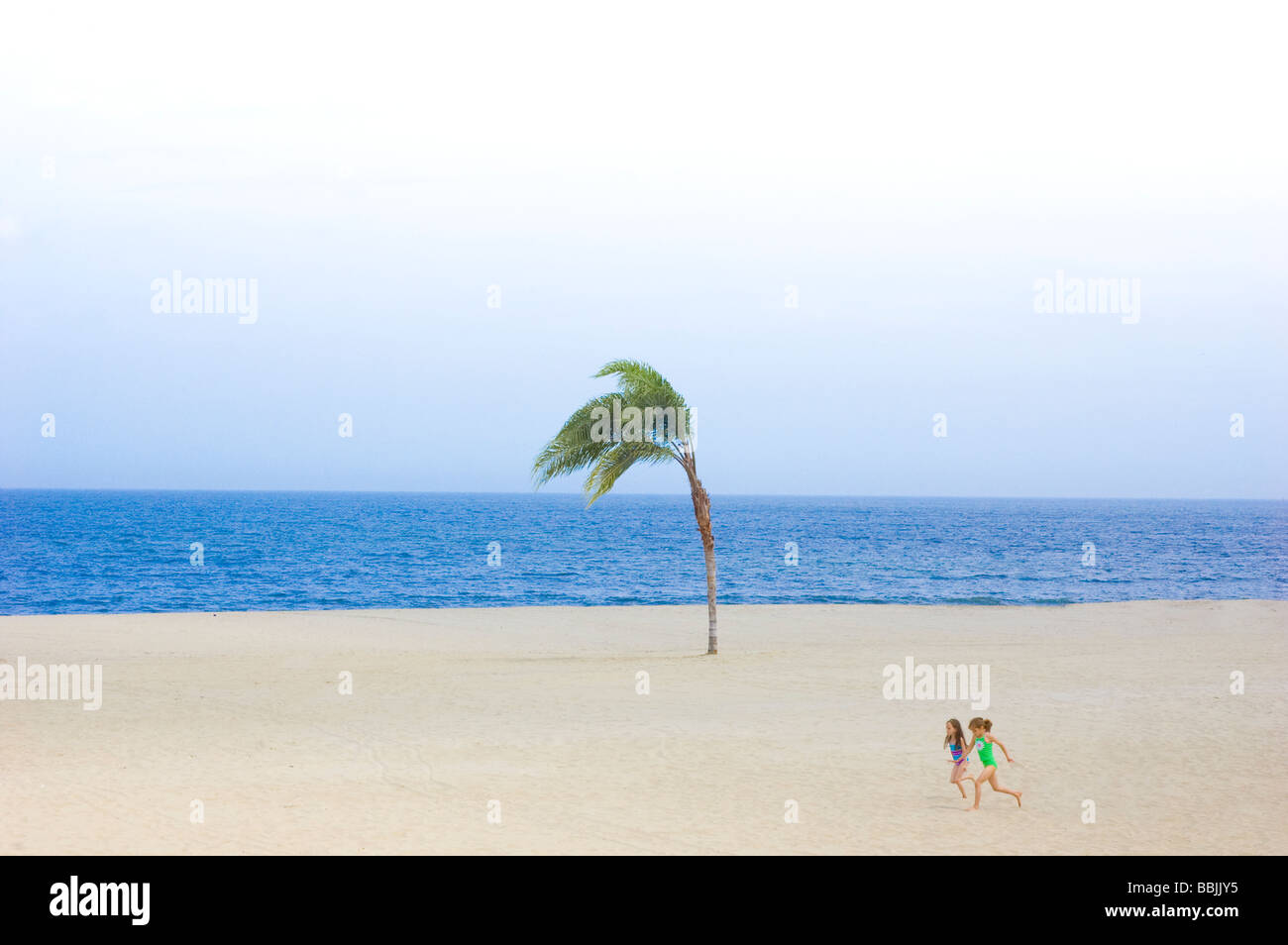 Photo de deux simples enfants courir sur la plage avec palmier et de l'océan Banque D'Images