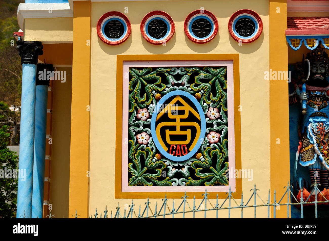 Fenêtre d'ornement sur le mur avant du temple de Cao Dai à Vung Tau, avec le mot 'CAO' dans sa conception. Banque D'Images