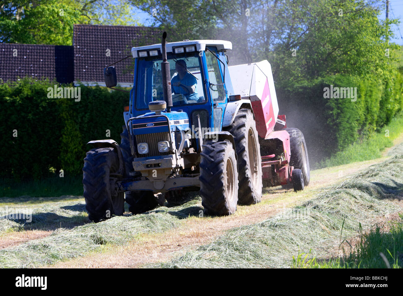 Remorquage de presse du tracteur pour couper l'herbe recueille la production d'ensilage County Down Irlande du Nord uk Banque D'Images