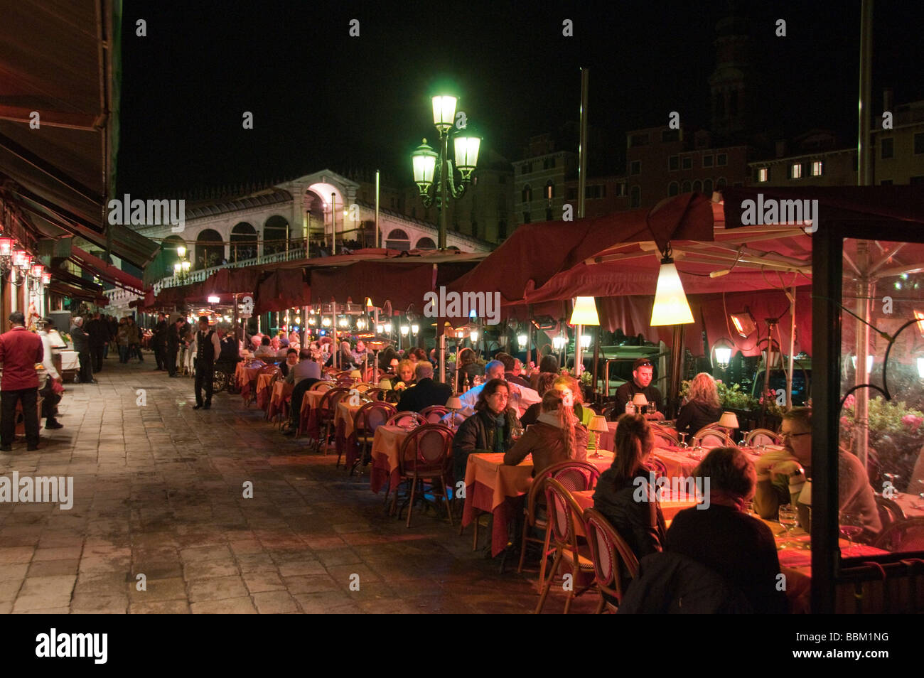 Salle de restaurant en plein air donnant sur le Grand Canal de nuit avec derrière le pont du Rialto Riva del Vin Rialto Venise Italie Banque D'Images