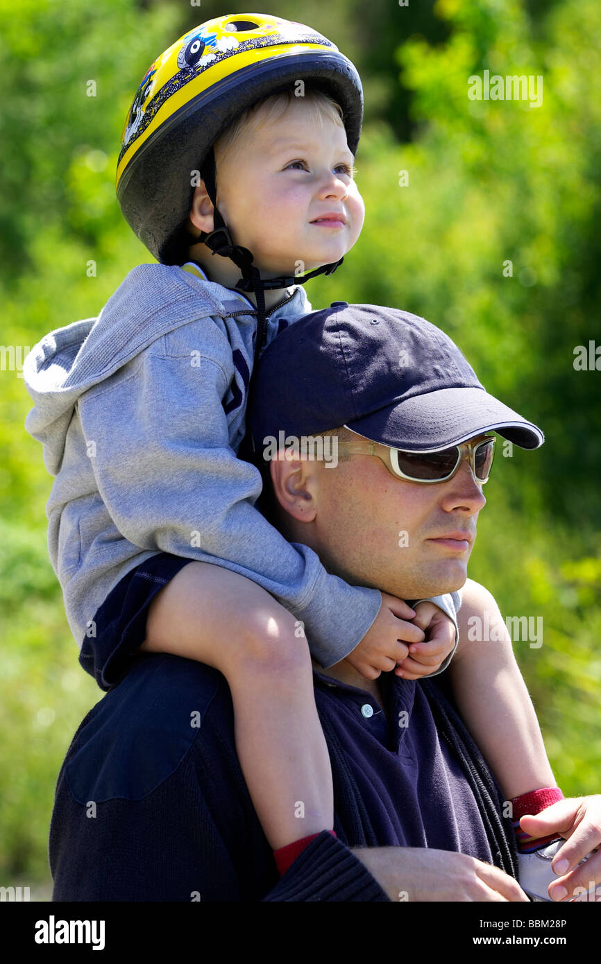 Boy wearing helmet assis sur les épaules du père Banque D'Images