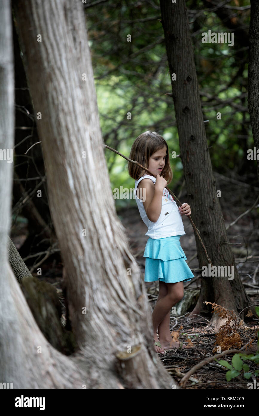 Fille qui marche à travers bois holding stick, Ontario Banque D'Images