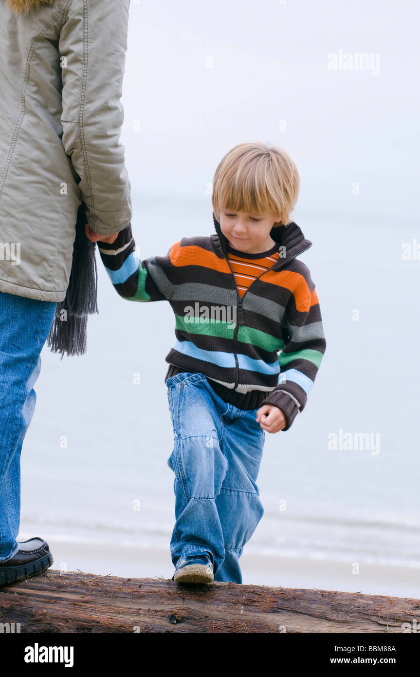 Jeune garçon tenant la main de femme comme ils marchent sur beach, Vancouver, Colombie-Britannique Banque D'Images