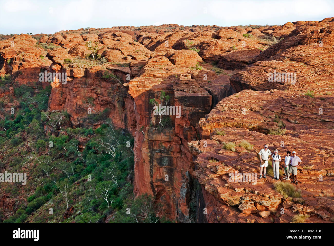 L'Australie, Territoire du Nord. Les randonneurs pause au bord d'un précipice entre les formations de roche rouge à Kings Canyon. Banque D'Images