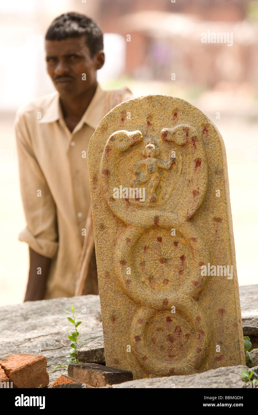 Un Indien se tient derrière un héros pierre dans les régions rurales du Tamil Nadu, Inde. Les pierres enregistrer les oeuvres de héros qui sont tombés au combat. Banque D'Images