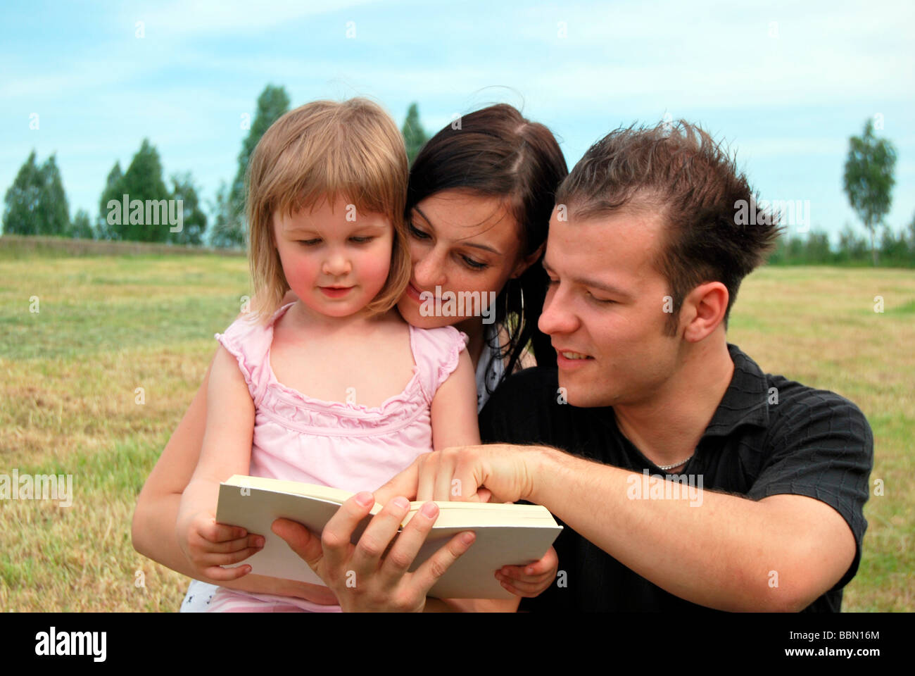 Le bonheur de la famille, mère, père et enfant lisant un livre Banque D'Images