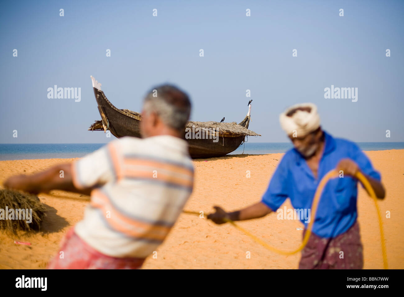 Christian indien tirant dans les filets des pêcheurs sur la plage avec un bateau en bois traditionnel fabriqué à la main en arrière-plan. Banque D'Images Christian indien tirant dans les filets des pêcheurs sur la plage avec un bateau en bois traditionnel fabriqué à la main en arrière-plan. Banque D'Images