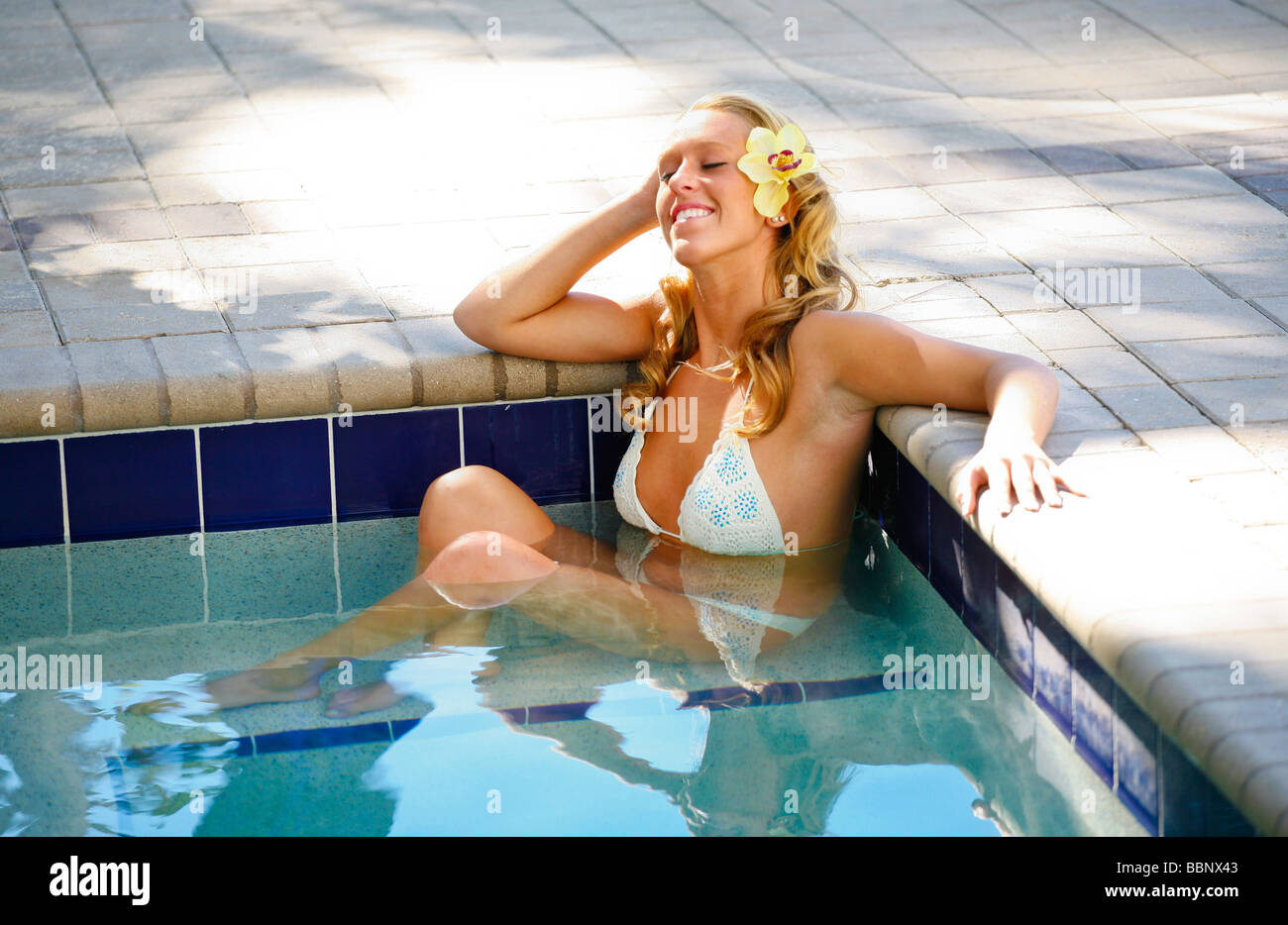 Jeune femme blonde se détendre dans un bain à remous extérieur en vacances dans un spa. Banque D'Images