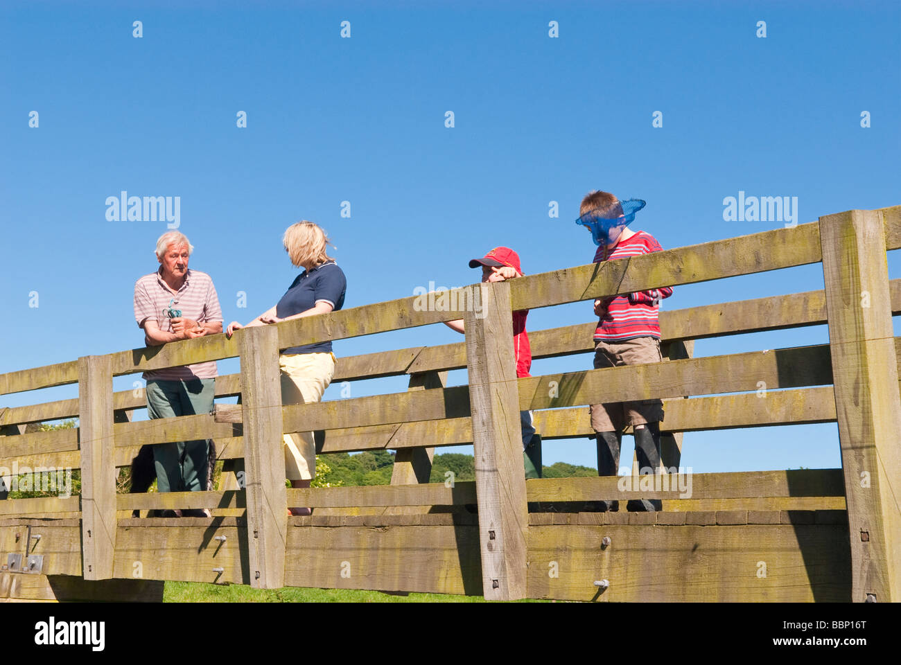 Un groupe de quatre membres de la famille de deux adultes et deux enfants debout sur un pont dans un cadre rural à la campagne britannique Banque D'Images