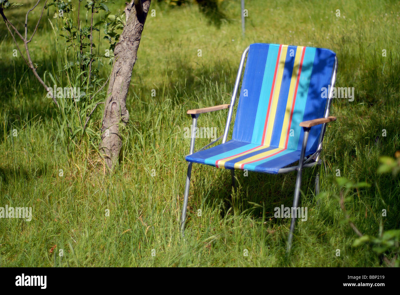 Un style rétro des années 70 chaise longue sur une pelouse en été envahi Banque D'Images
