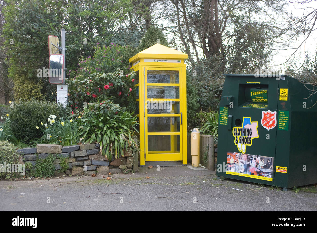 Une cabine téléphonique jaune à côté d'un bac de recyclage Banque D'Images