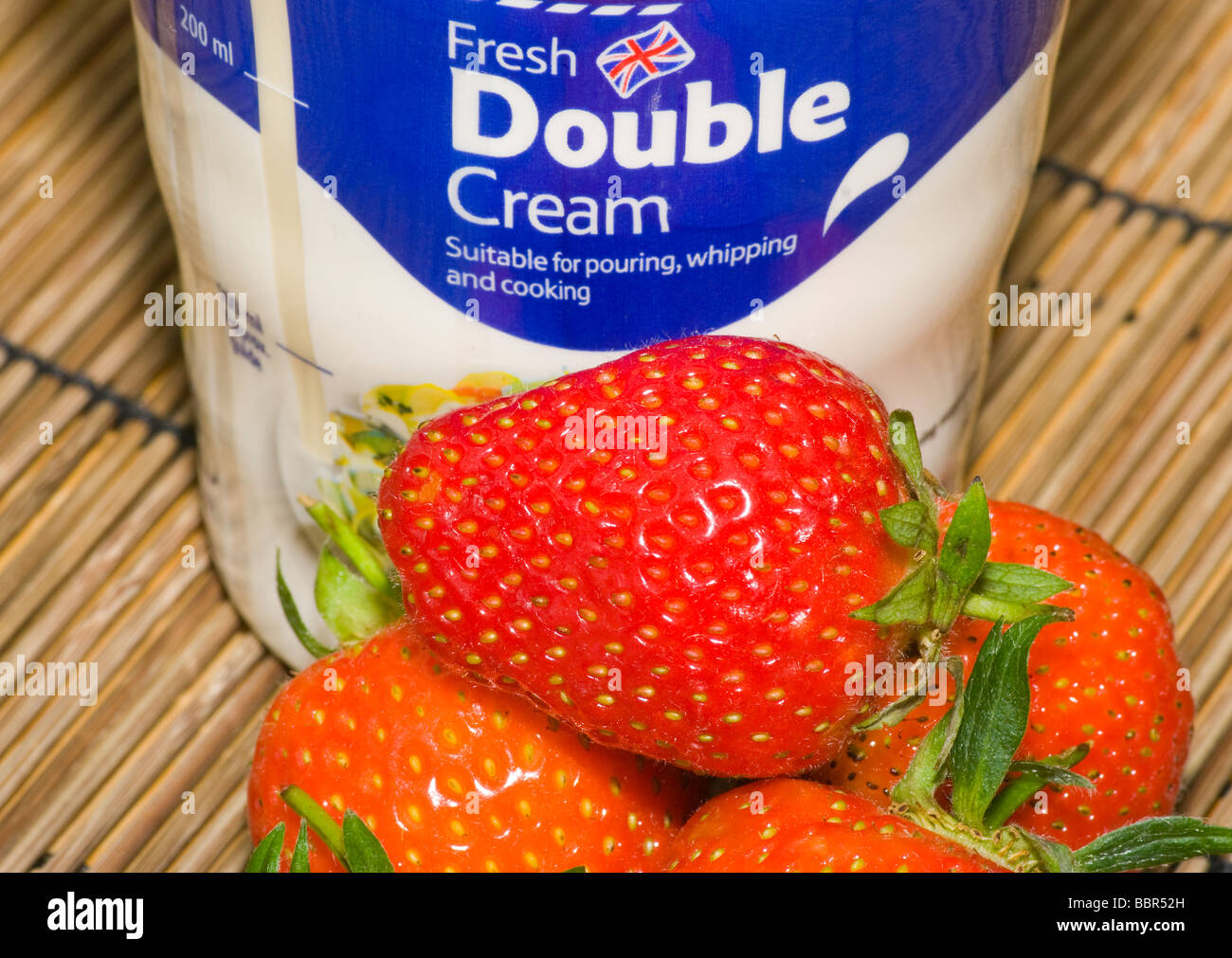 Fraises fraîches avec un pot de crème double Banque D'Images